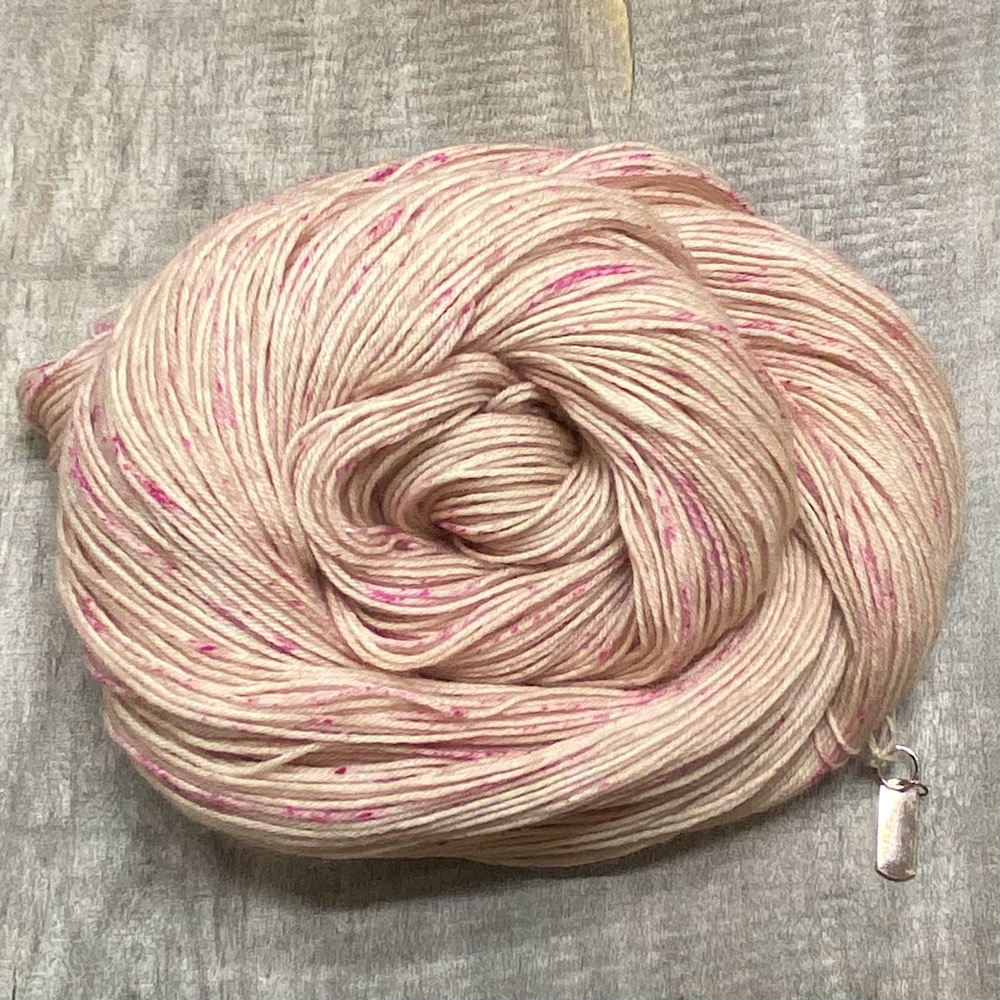 A swirled skein of hand dyed, pure BFL wool, in colour 'Pink Dream'. Dyed in a sleepy beige, then sprinkled over in a deep pink,