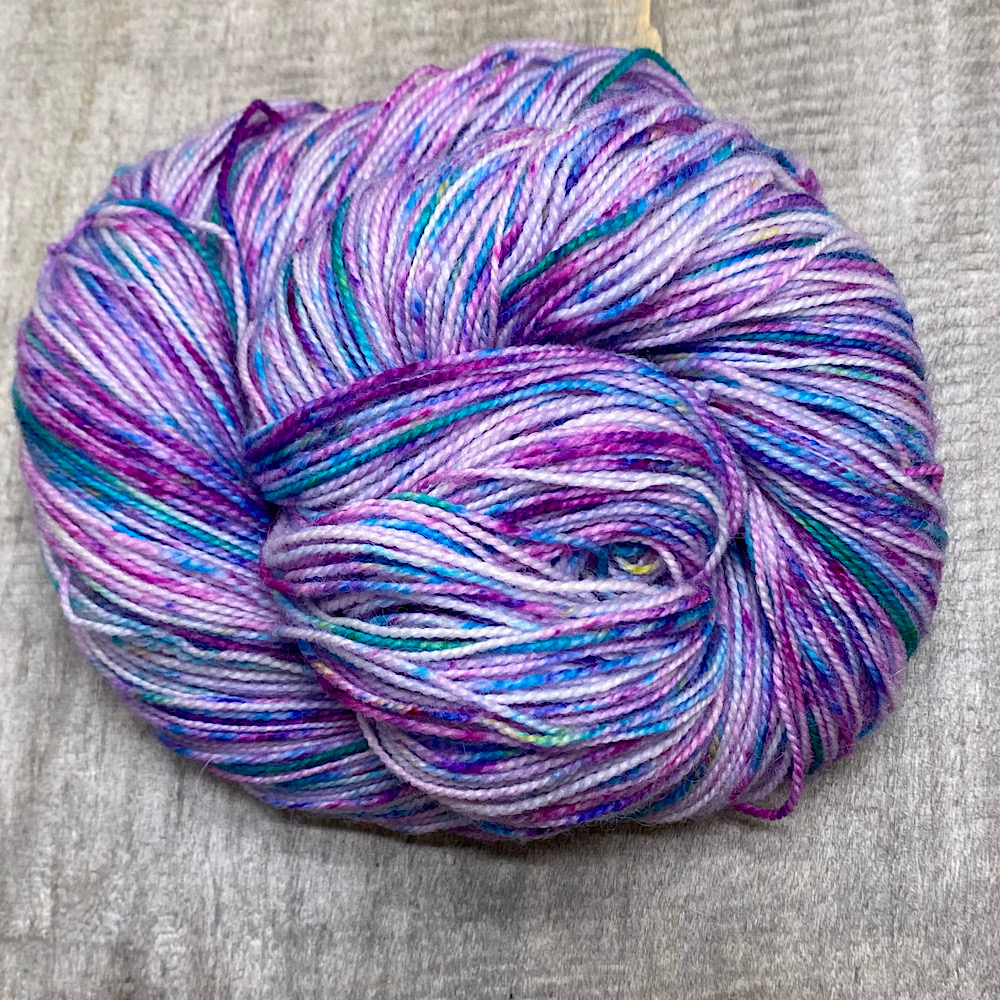A swirl of pure BFL wool hand dyed in 'Pretty Perfect' - speckled in lilacs, greens and turquoises